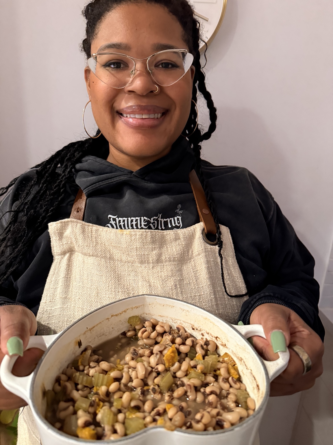 Maya holding a pot of black-eyed peas while wearing Fmme Strng apparel