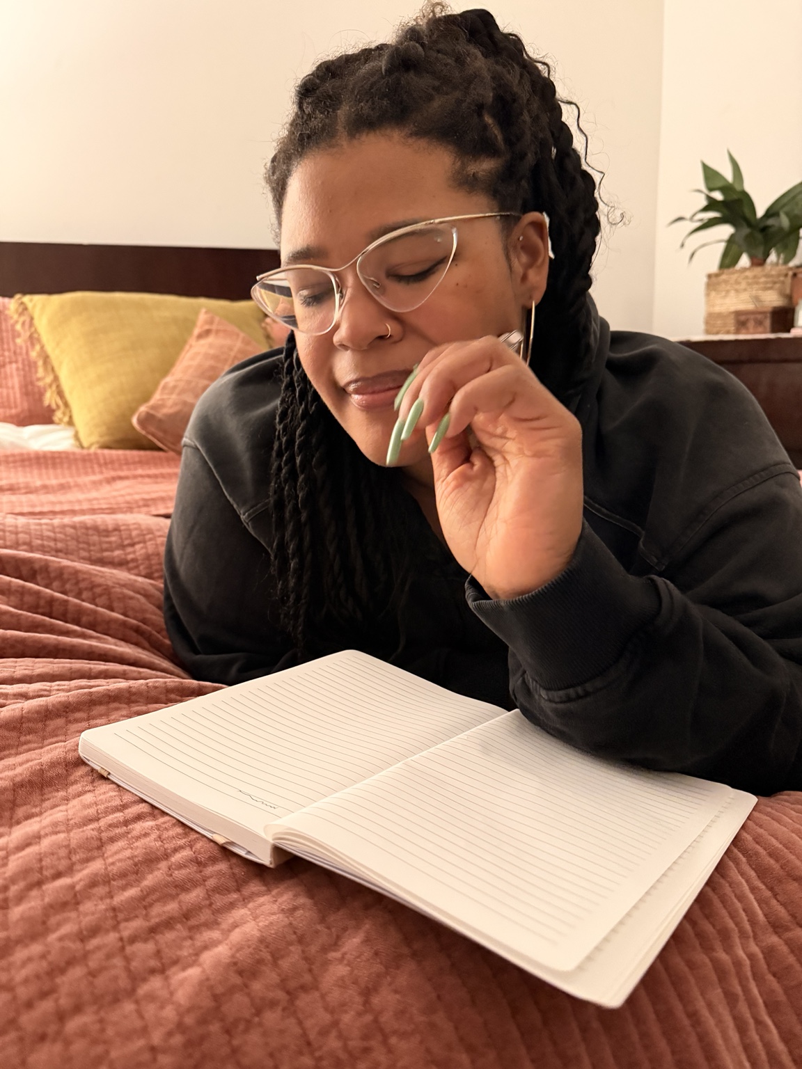 Maya journaling on a bed with the Fmme Strng Ritual Journal