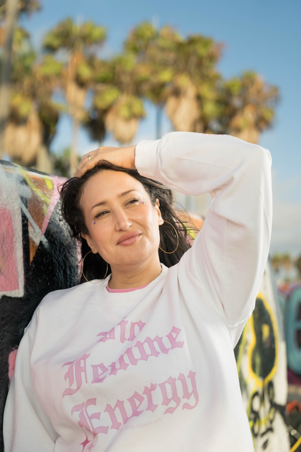 Sara wearing the Big Fmme Energy sweatshirt beside a colorful Venice wall